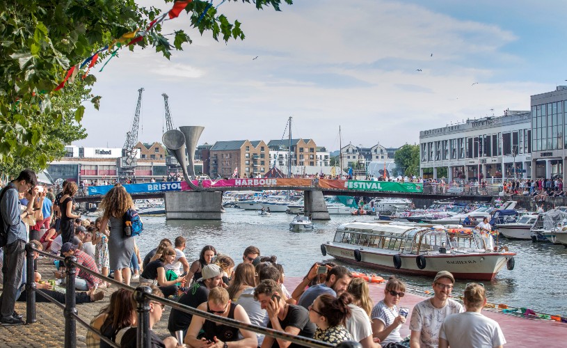 People around the harbour during Bristol Harbour Festival with a view of Pero's Bridge and the M Shed cranes